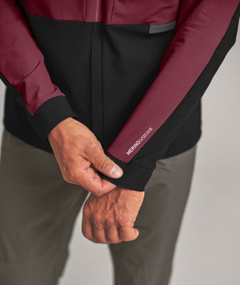 Ein Mann passt den Ärmel einer Jacke mit der Aufschrift MERINOINSIDE an. Ein Mann passt den Ärmel einer Jacke mit der Aufschrift MERINOINSIDE an.