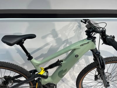 Grünes Mountain-Elektrofahrrad mit Dämpfer und schwarzem Sattel. Grünes Mountain-Elektrofahrrad mit Dämpfer und schwarzem Sattel.
