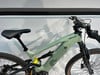 Grünes Mountain-Elektrofahrrad mit Dämpfer und schwarzem Sattel.