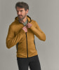 Ein Mann schließt eine gelbe Jacke mit Reißverschluss und grauen Einsätzen.