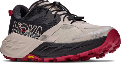Herren-Trailrunning-Schuh Hoka Speedgoat 7 GTX in Beige und Schwarz mit roter Sohle. Herren-Trailrunning-Schuh Hoka Speedgoat 7 GTX in Beige und Schwarz mit roter Sohle.