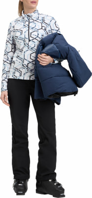 Eine Frau in Skischuhen hält eine dunkelblaue Daunenjacke. Eine Frau in Skischuhen hält eine dunkelblaue Daunenjacke.