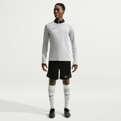Ein Mann in einem grauen Langarmshirt, schwarzer Hose und weißen Socken.