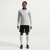 Ein Mann in einem grauen Langarmshirt, schwarzer Hose und weißen Socken.