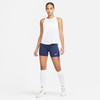 Eine Frau in einem weißen Tanktop und dunkelblauen Shorts mit weißen Socken.
