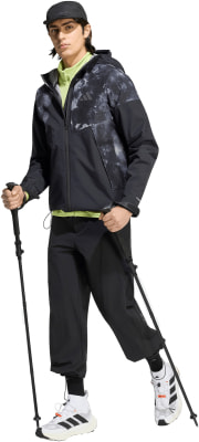 Ein Mann in schwarzer Kleidung mit Batikmuster und Trekkingstöcken. Ein Mann in schwarzer Kleidung mit Batikmuster und Trekkingstöcken.