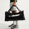 Ein Mann trägt eine schwarze Nike Sporttasche mit großem weißem Logo.