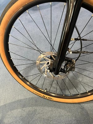 Vorderrad eines schwarzen Fahrrads mit braunem Reifen und Scheibenbremse. Vorderrad eines schwarzen Fahrrads mit braunem Reifen und Scheibenbremse.