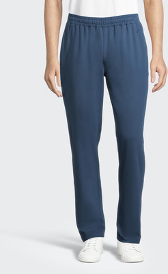 Ein Mann in blauen Jogginghosen und weißen Turnschuhen steht vor weißem Hintergrund. Ein Mann in blauen Jogginghosen und weißen Turnschuhen steht vor weißem Hintergrund.
