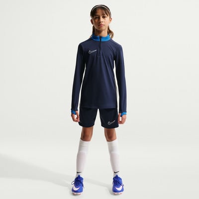 Mädchen in dunkelblauem Nike-Trikot und Shorts, weißen Socken und blauen Fußballschuhen. Mädchen in dunkelblauem Nike-Trikot und Shorts, weißen Socken und blauen Fußballschuhen.