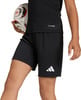 Ein Junge hält einen Fußball in schwarzen Shorts mit Adidas-Logo.