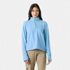 Frau in einem blauen Pullover mit Stehkragen und kurzem Reißverschluss und einer beigen Hose.