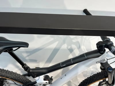 Teil eines weißen Mountainbikes mit schwarzem Rahmen und Sattel auf einem Ständer. Teil eines weißen Mountainbikes mit schwarzem Rahmen und Sattel auf einem Ständer.
