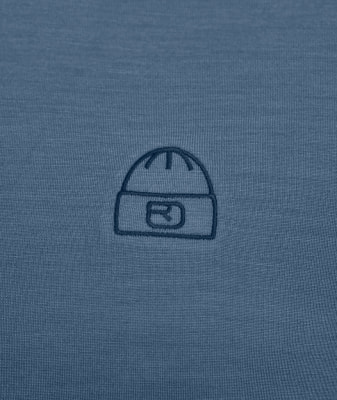 Ein gesticktes Mützen-Logo auf einem blauen Shirt.