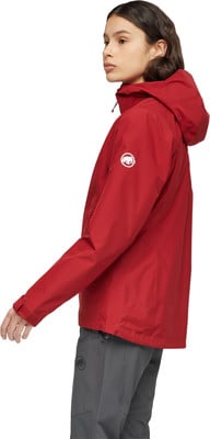 Frau in roter Jacke und grauer Hose mit Mammut-Logo. Frau in roter Jacke und grauer Hose mit Mammut-Logo.