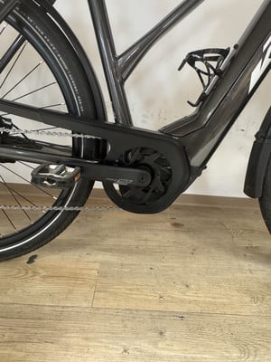 Detail des E-Bike-Rahmens mit Kette und Kurbeln auf Holzboden. Detail des E-Bike-Rahmens mit Kette und Kurbeln auf Holzboden.
