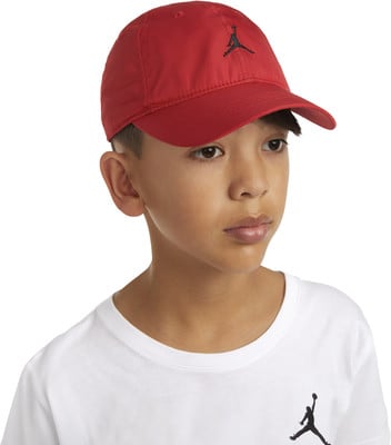 Ein Junge in einer roten Kappe mit Jordan-Logo und weißem T-Shirt. Ein Junge in einer roten Kappe mit Jordan-Logo und weißem T-Shirt.