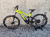 Ein grünes Genesis E-Bike steht auf einem Ständer vor einer Betonwand.