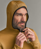 Ein Mann schließt eine gelbe Kapuzenjacke mit schwarzer Paspel.