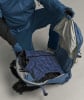 Eine Person in blauer Kleidung packt eine blaue Daunenweste in einen Rucksack.