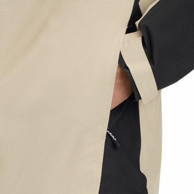 Detail einer Jacke aus beige und schwarzem Stoff, Tasche mit Hand darin. Detail einer Jacke aus beige und schwarzem Stoff, Tasche mit Hand darin.