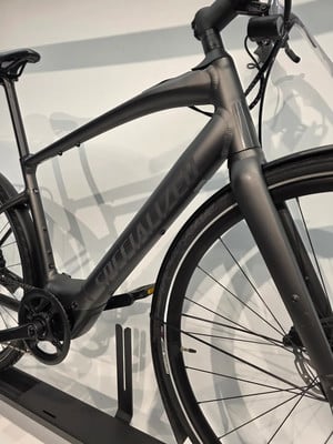 Nahaufnahme des Rahmens eines dunkelgrauen Specialized E-Bikes mit sichtbarem Schriftzug. Nahaufnahme des Rahmens eines dunkelgrauen Specialized E-Bikes mit sichtbarem Schriftzug.