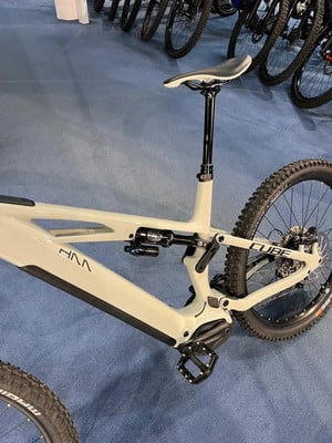 Hellbeiges Cube Mountain-E-Bike mit Federung und schwarzen Pedalen. Hellbeiges Cube Mountain-E-Bike mit Federung und schwarzen Pedalen.