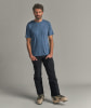 Ein Mann in einem blauen T-Shirt und schwarzer Hose mit Skischuhen.