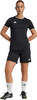 Eine Frau in einem schwarzen Fußballtrikot und Shorts mit weißen Socken und Fußballschuhen.