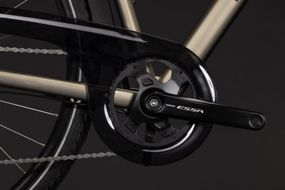 Detailaufnahme der Fahrradkurbel und Kette vor dunklem Hintergrund.