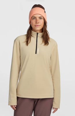Ein Model trägt einen beige Fleece-Pullover mit kurzem Reißverschluss und eine rosa-braune Mütze. Ein Model trägt einen beige Fleece-Pullover mit kurzem Reißverschluss und eine rosa-braune Mütze.