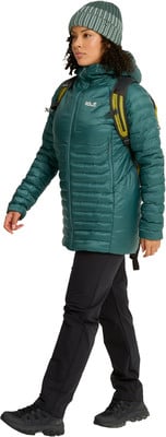 Eine Frau in einer grünen Daunenjacke, schwarzer Mütze und Hose geht. Eine Frau in einer grünen Daunenjacke, schwarzer Mütze und Hose geht.