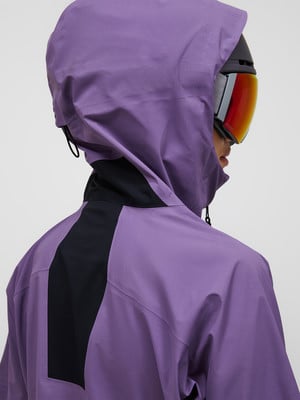 Rückansicht einer Person in einer lila Kapuzenjacke mit Skibrille. Rückansicht einer Person in einer lila Kapuzenjacke mit Skibrille.