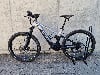 Ein Genesis E-Mountainbike steht auf Pflastersteinen vor einer Betonwand.
