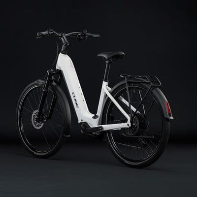 Ein weißes Cube E-Bike mit schwarzen Akzenten und Gepäckträger vor dunklem Hintergrund. Ein weißes Cube E-Bike mit schwarzen Akzenten und Gepäckträger vor dunklem Hintergrund.
