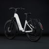 Ein weißes Cube E-Bike mit schwarzen Akzenten und Gepäckträger vor dunklem Hintergrund.
