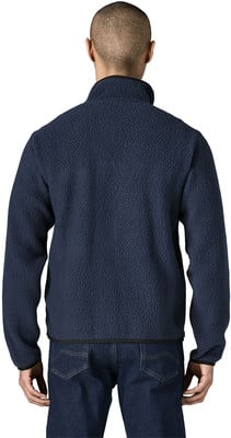 Mann von hinten in dunkelblauem Fleece-Pullover und Jeans.