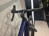 Detail des Lenkers eines violetten Gravelbikes mit Lenkerband und Bremshebeln.