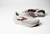Weiße Brooks Laufschuhe mit rosa und dunkelbraunen Details auf weißem Hintergrund.