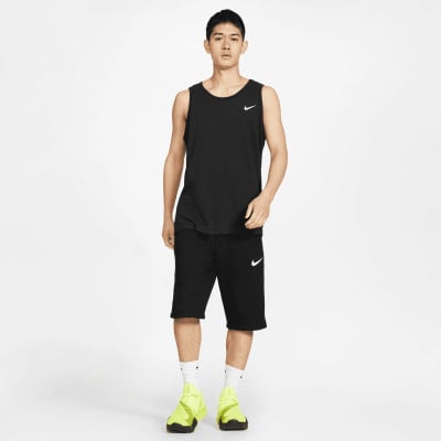 Mann in schwarzem Tanktop und Nike-Shorts mit neongelben Schuhen. Mann in schwarzem Tanktop und Nike-Shorts mit neongelben Schuhen.