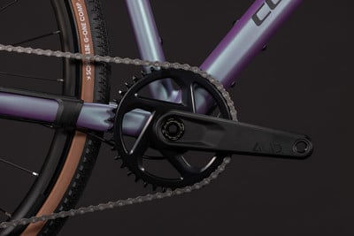 Detail des Kettenblatts und der Kette an einem lila Fahrrad mit ACID-Logo. Detail des Kettenblatts und der Kette an einem lila Fahrrad mit ACID-Logo.