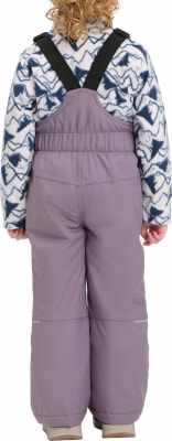 Rückansicht eines Mädchens in Latzhose und gemusterter Jacke.