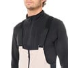 Ein Mann in einem schwarzen Fleece-Oberteil und einer hellen Latzhose.