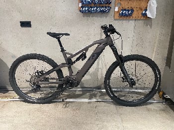 Graues E-Bike mit Federung in Innenräumen, Steckdosen an der Wand.