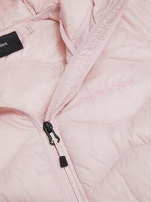 Eine rosa Daunenjacke mit Peak Performance Logo und schwarzem Reißverschluss. Eine rosa Daunenjacke mit Peak Performance Logo und schwarzem Reißverschluss.