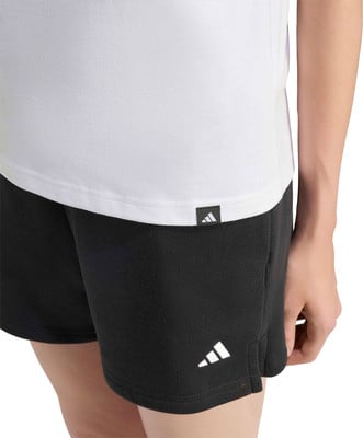 Detail eines weißen T-Shirts und schwarzer Shorts mit Adidas-Logo.