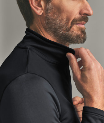 Ein Mann richtet den Kragen eines schwarzen Langarmshirts. Ein Mann richtet den Kragen eines schwarzen Langarmshirts.