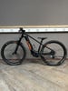 Schwarzes KTM E-Bike mit orangefarbenen Details auf Holzboden.