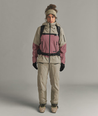 Eine Frau in Skibekleidung mit Rucksack und Skischuhen. Eine Frau in Skibekleidung mit Rucksack und Skischuhen.