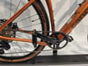 Orangefarbenes Fahrrad mit Nahaufnahme von Kurbeln, Kassette und Kette.